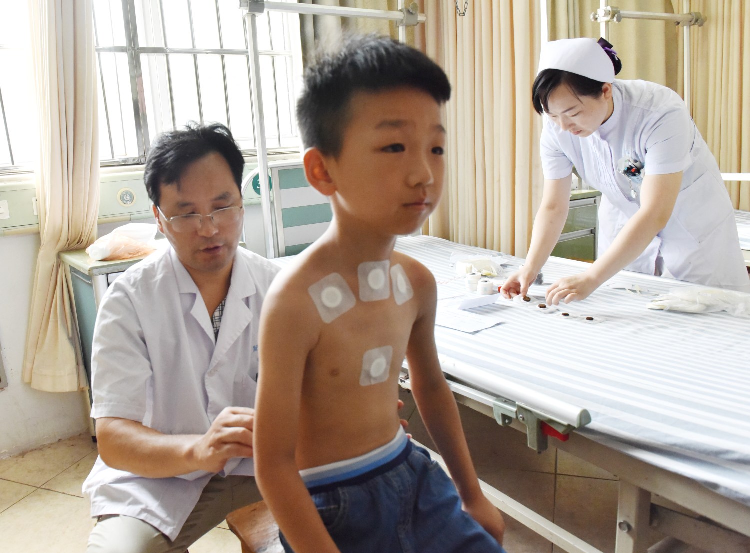 A doctor sticks the Sanfu Paste, a traditional Chinese medicine treatment in the hottest days of summer, on a boy at a hospital in Hefei city, east China's Anhui province, 17 July 2018.Sanfu Paste, also known as dog-days paste, is a traditional Chinese medicine treatment. During the treatment, patients will be stuck with the Chinese medicine contained in the paste on acupoints during the dog days, the hottest and most sultry days of summer. This treatment is regarded to be able to cure such chronic diseases like asthma. Monday is the first day of dog days and hospitals are crammed with citizens for the Sanfu Paste.No Use China. No Use France.
