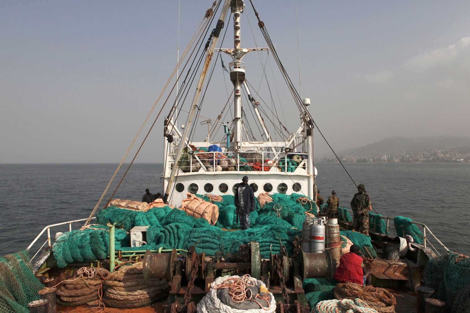 Sierra Leonean security forces supervise the crew on board the Marampa 803, a vessel apprehended for alleged illegal fishing activities, that has been moored off the West African country's capital Freetown January 21, 2012. West Africa, recognized as one of the world's richest fisheries grounds teeming with snapper, grouper, sardines, mackerel and shrimp, loses up to $1.5 billion worth of fish each year to vessels fishing in protected zones or without proper equipment or licenses. Widespread corruption and a continuing lack of resources for enforcement mean huge foreign trawlers often venture into areas near the coast that are reserved exclusively for artisanal fishermen, allowing them to drag off tonnes of catch and putting at risk the livelihoods of millions of local people. Picture taken January 21, 2012. To match Feature WESTAFRICA-FISHING/   REUTERS/Simon Akam (SIERRA LEONE - Tags: SOCIETY BUSINESS ENVIRONMENT FOOD ANIMALS)