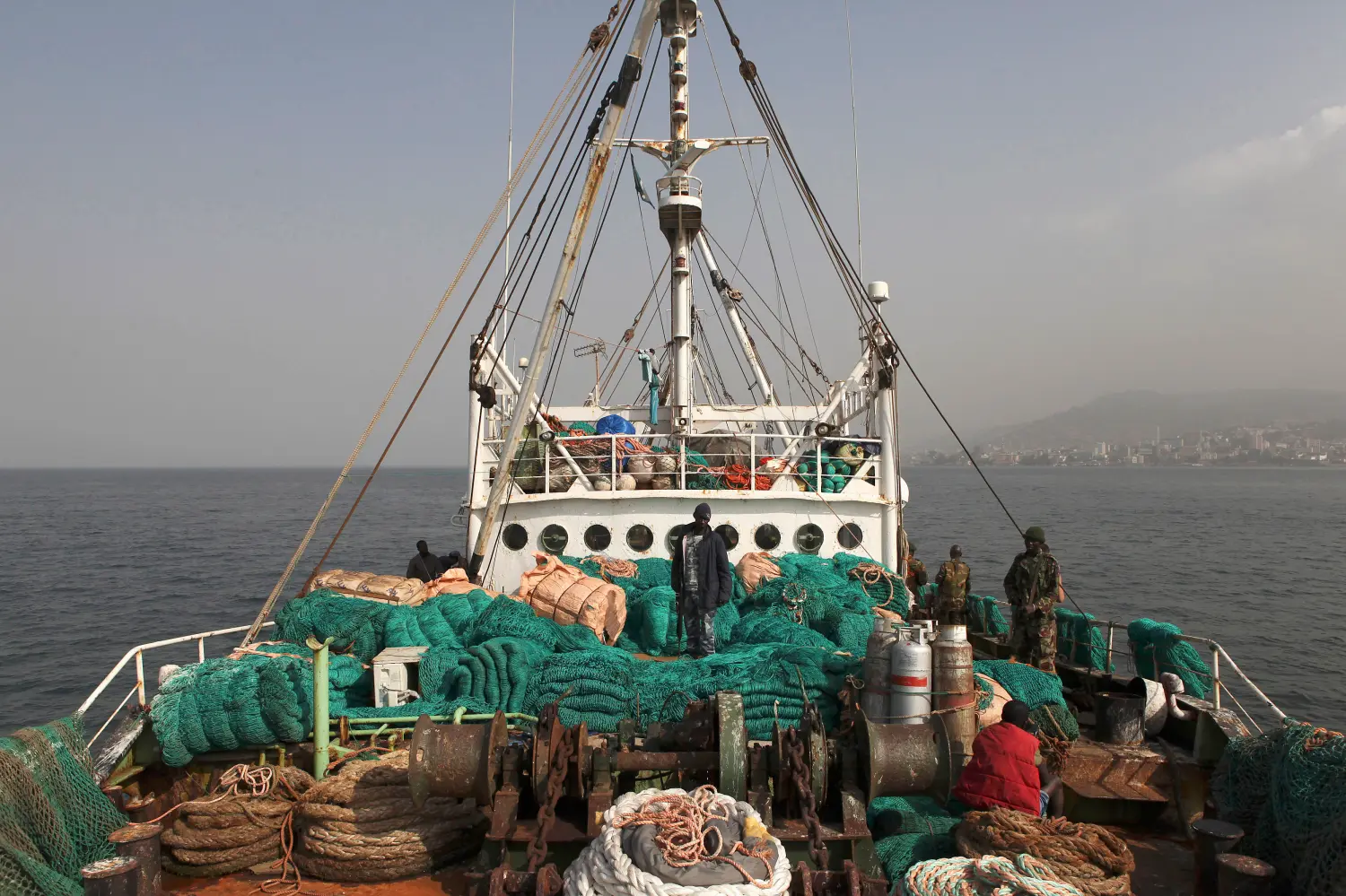 Sierra Leonean security forces supervise the crew on board the Marampa 803, a vessel apprehended for alleged illegal fishing activities, that has been moored off the West African country's capital Freetown January 21, 2012. West Africa, recognized as one of the world's richest fisheries grounds teeming with snapper, grouper, sardines, mackerel and shrimp, loses up to $1.5 billion worth of fish each year to vessels fishing in protected zones or without proper equipment or licenses. Widespread corruption and a continuing lack of resources for enforcement mean huge foreign trawlers often venture into areas near the coast that are reserved exclusively for artisanal fishermen, allowing them to drag off tonnes of catch and putting at risk the livelihoods of millions of local people. Picture taken January 21, 2012. To match Feature WESTAFRICA-FISHING/   REUTERS/Simon Akam (SIERRA LEONE - Tags: SOCIETY BUSINESS ENVIRONMENT FOOD ANIMALS)