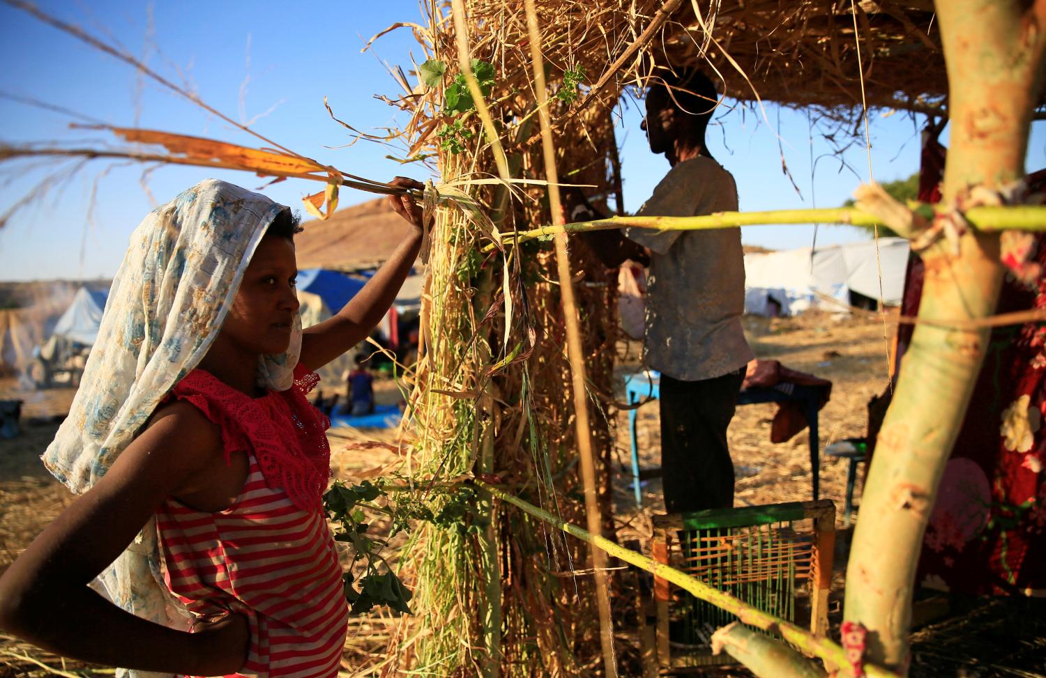 An Ethiopian refugee couple who fled Tigray region, build a makeshift shelter within the Um-Rakoba camp in Al-Qadarif state, on the border in Sudan December 11, 2020. REUTERS/Mohamed Nureldin Abdallah
