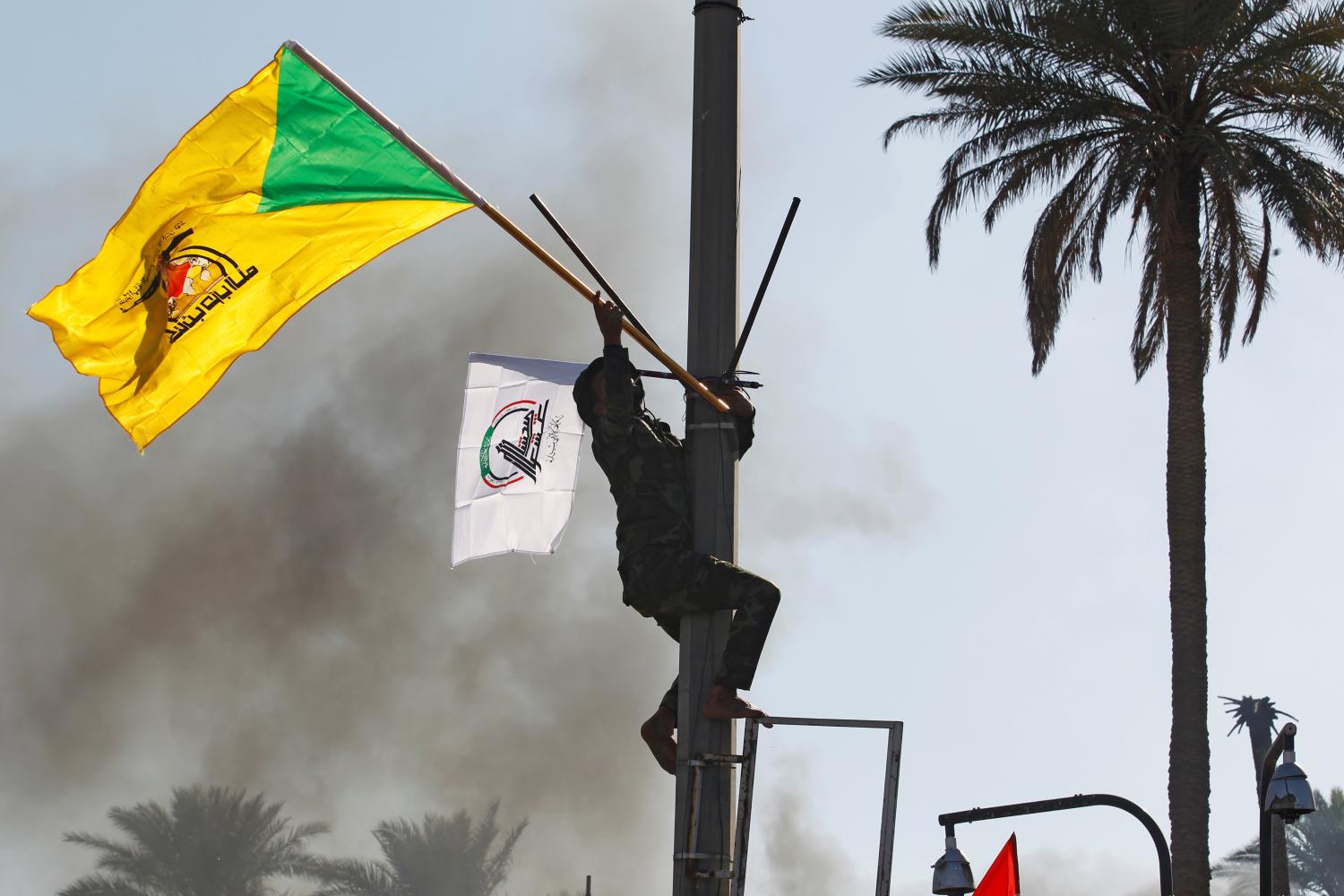 A member of Hashd al-Shaabi (paramilitary forces) holds a flag of Kataib Hezbollah militia group during a protest to condemn air strikes on their bases, in Baghdad, Iraq December 31, 2019. REUTERS/Khalid al-Mousily