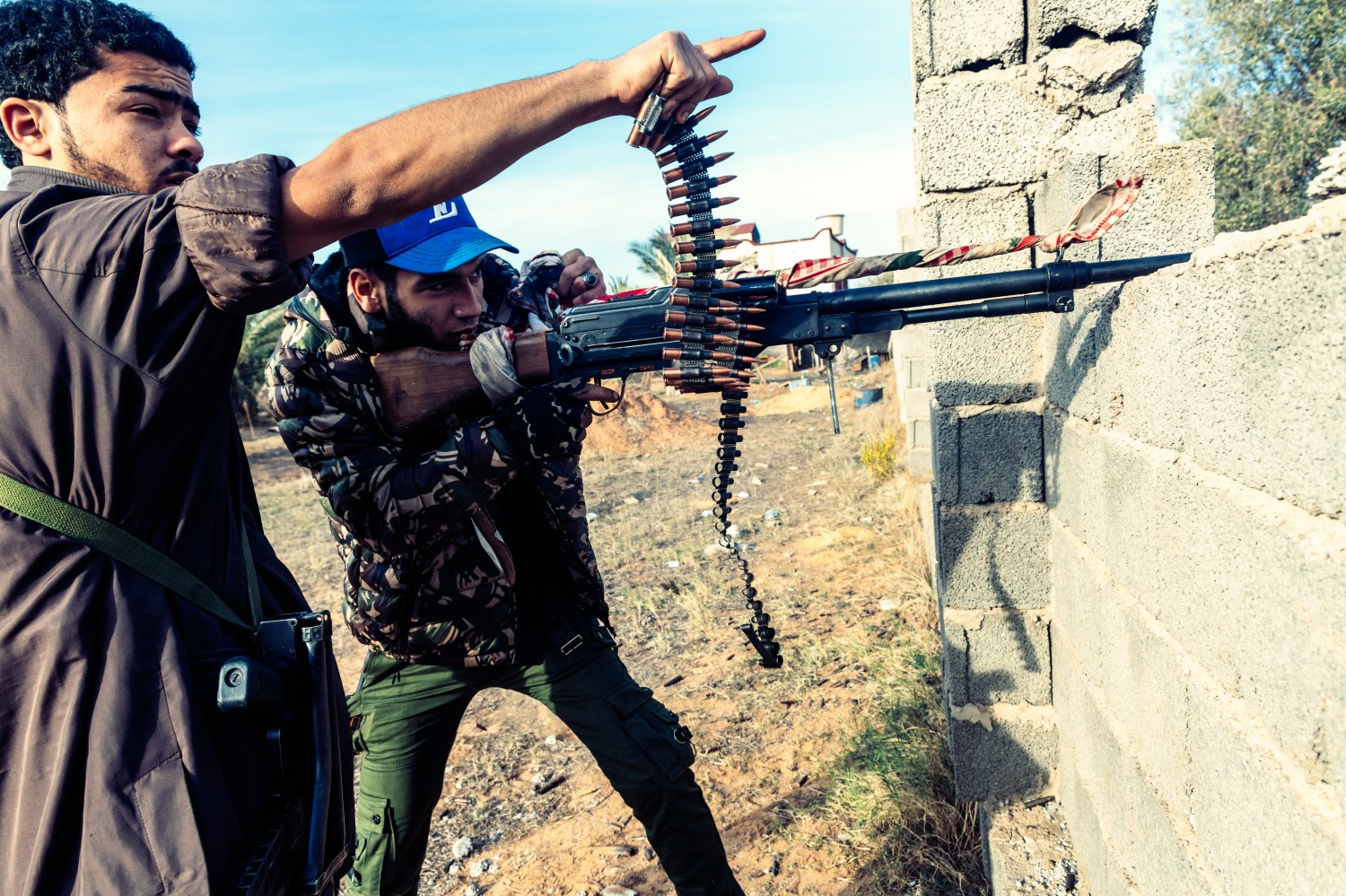 On the front line of Al Swani during the clashes, a fighter of Brigade 610 (GNA) fires with his machine-gun while his comrade points his finger towards the enemy. Since April, the Libyan National Army (LNA) led by Khalifa Haftar is attempting to take control of Tripoli defended by the forces of UN-backed recognised Government of National Accord of Fayez el-Sarraj (GNA). Libya, outskirts of Tripoli, December 6, 2019. Sur la ligne de front de Al Swani pendant les affrontements, un combattant de la brigade 610 (GAN) tire avec sa mitraille alors que son camarade pointe du doigt l'ennemi. Depuis avril, l'armee nationale Libyenne (LNA) dirigee par Khalifa Haftar essaie de prendre le control de Tripoli defendu par les forces du gouvernement d'accord national de Fayez al-Sarraj, soutenu par l'onu (GAN). Libye, banlieue de Tripoli, 6 decembre 2019.NO USE FRANCE