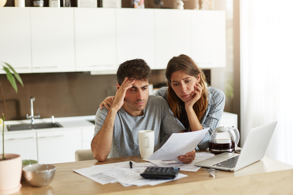 Unhappy American couple managing home accounts in kitchen