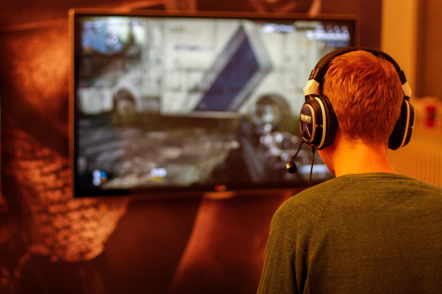 A gamer wearing headphones plays the Call of Duty first person shooter.