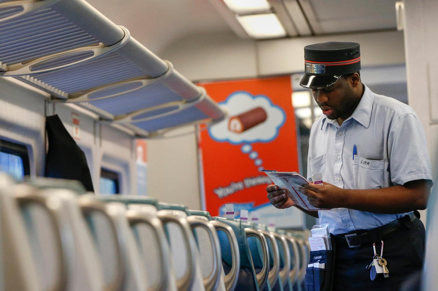 A Long Island Railroad train conductor looks at a train schedule aboard a train bound for New York July 17, 2014. A threatened strike on New York's Long Island Rail Road has been averted after a tentative contract agreement was reached on Thursday, one of the labor unions involved in the negotiations said on its website. The state-controlled Metropolitan Transportation Authority and the coalition of eight unions representing about 5,400 rail workers have been involved in fraught negotiations to replace a workers' contract that expired in 2010. REUTERS/Shannon Stapleton (UNITED STATES  - Tags: TRANSPORT CIVIL UNREST BUSINESS EMPLOYMENT)