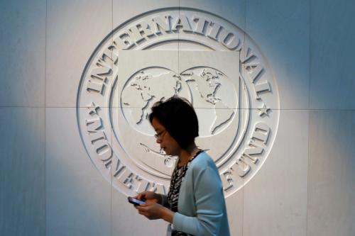 A woman walks past the International Monetary Fund (IMF) logo at its headquarters in Washington, U.S.