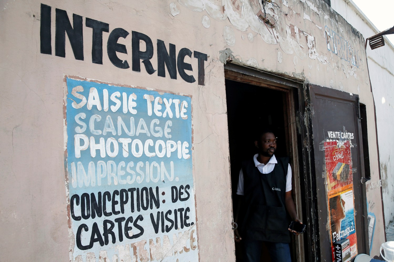 The owner of an internet cafe in Congo stands at the door of his business.