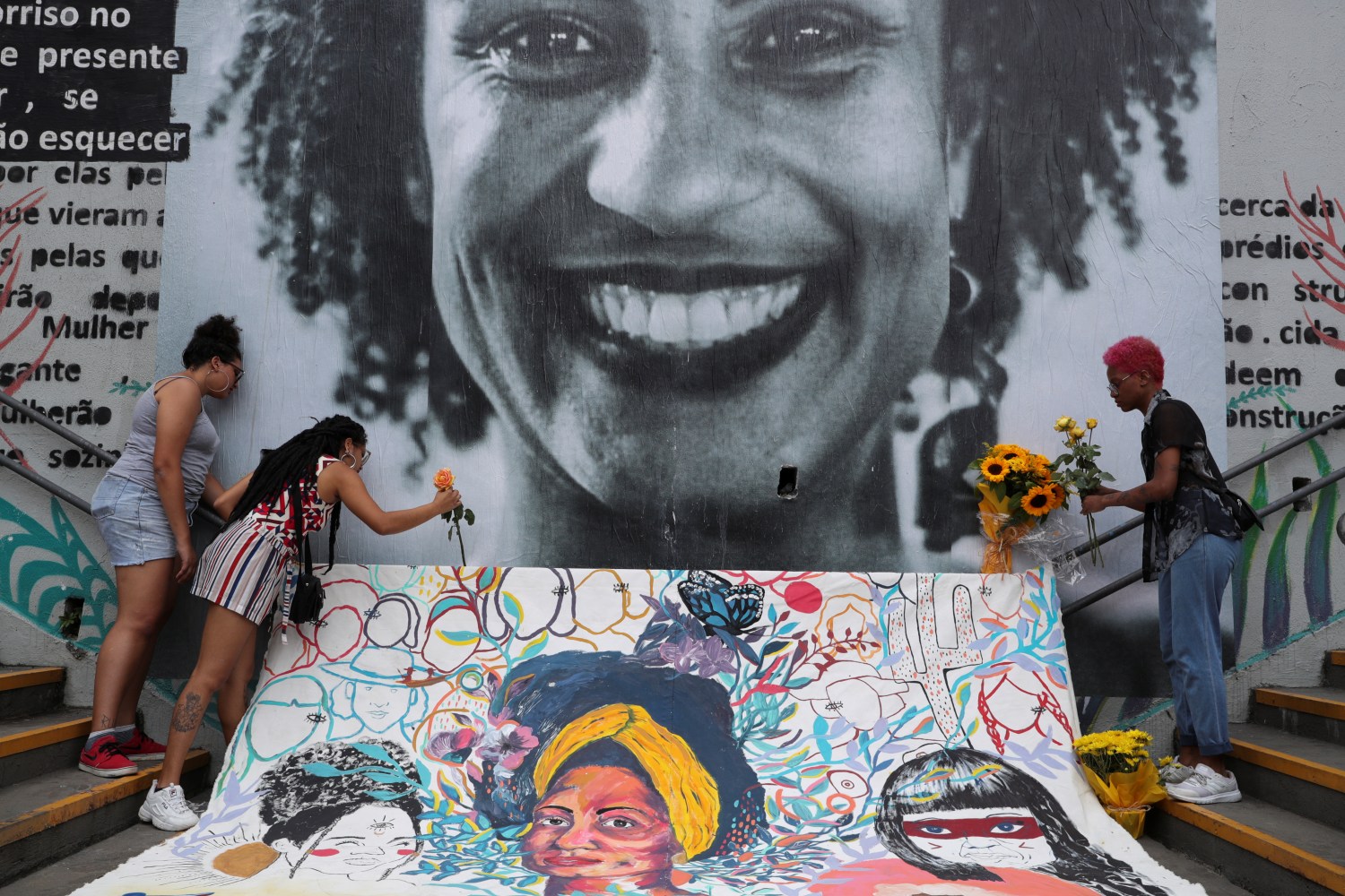 Women lay flowers at a mural of the murdered human rights activist Marielle Franco.