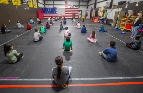 Students at Hiland Park Elementary School sit on dots in their physical education class that keep them six feet apart Tuesday, February 23, 2021.001 022321 Quarantining Changes
