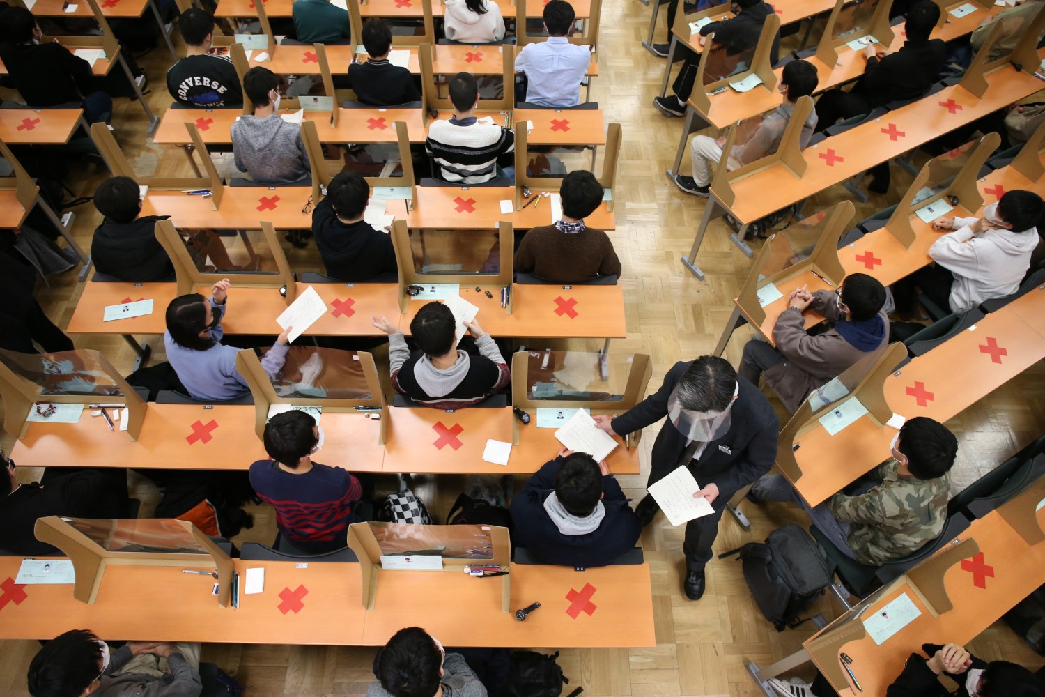 The secondary examination of the national and public universities starts at the Tokyo University in Bunkyo Ward, Tokyo on February 25, 2021. The examinees wearing face masks maintain social distance while testing amid a pandemic of the new coronavirus COVID-19. The examiners wear face shields and transparent partitions are set on each desk.   ( The Yomiuri Shimbun via AP Images )