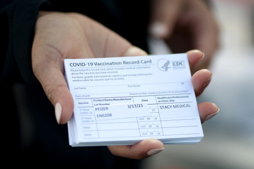A medical worker holds Pfizer coronavirus disease (COVID-19) vaccination cards at a mobile vaccination drive for essential food processing workers at Rose & Shore, Inc., in Vernon, Los Angeles