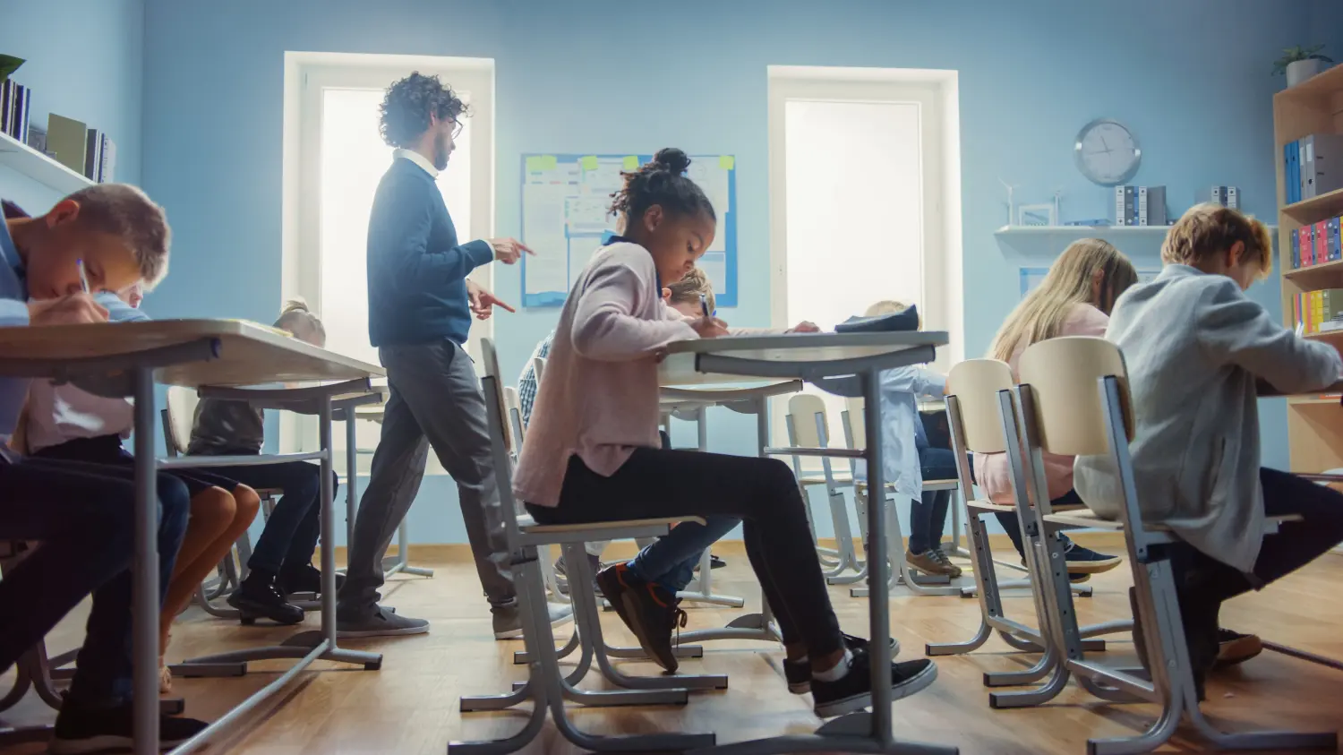 Students working in a classroom with a teacher walking around.