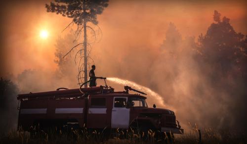 firefighter putting off fire while surrounded by a forest fire
