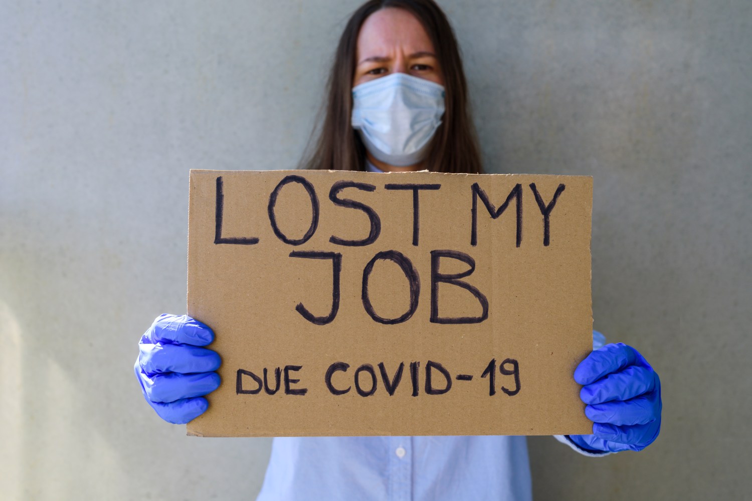 Woman office worker in blue shirt with cardboard sign LOST JOB. Jobless, unemployment due covid-19 concept.