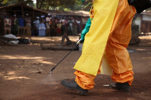 A member of the French Red Cross disinfects the area around a motionless person suspected of carrying the Ebola virus as a crowd gathers in Forecariah January 30, 2015. Health officials botched more than 20 Ebola blood tests in January and February which led to the release of at least four positive patients, two of whom later died, Guinea's anti-Ebola coordinator and other health officials told Reuters. Picture taken January 30, 2015. REUTERS/Misha Hussain (GUINEA - Tags: DISASTER HEALTH)
