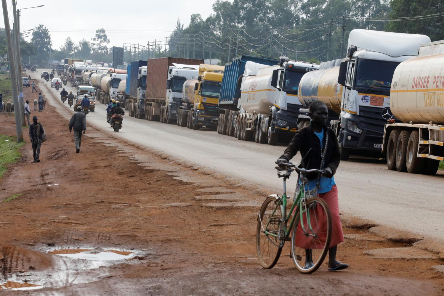 Woman walks past trucks waiting in a 10km queue to cross the Kenyan-Ugandan border in the town of Busia, Kenya November 14, 2020. Picture taken November 14, 2020. REUTERS/Baz Ratner