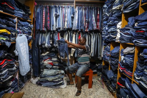A second-hand clothes vendor examines a jean jacket in his shop at the Yaba market, amid the coronavirus disease (COVID-19) outbreak, in Lagos, Nigeria March 23, 2020. Picture taken March 23, 2020. REUTERS/Temilade Adelaja