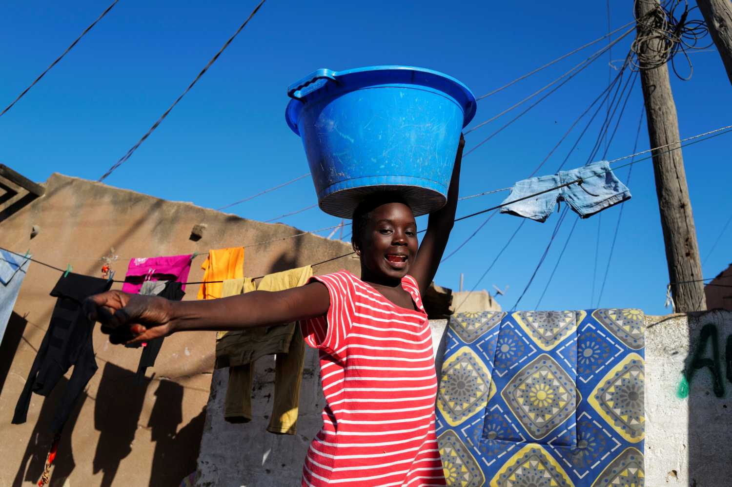 A girl reacts as she carries a bucket with laundry on her head while heading home as the spread of the coronavirus disease (COVID-19) continues, in Yoff neighbourhood, Dakar, Senegal January 26, 2021. REUTERS/Zohra Bensemra