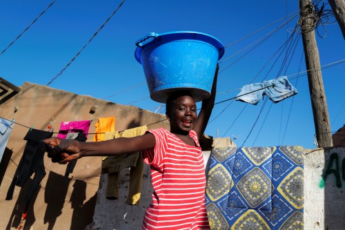 A girl reacts as she carries a bucket with laundry on her head while heading home as the spread of the coronavirus disease (COVID-19) continues, in Yoff neighbourhood, Dakar, Senegal January 26, 2021. REUTERS/Zohra Bensemra