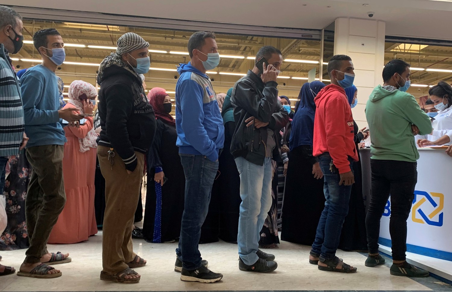 People wearing protective face masks wait in line in front of Al Ahli Bank of Kuwait (ABK) stand inside a Carrefour hypermarket ahead of Black Friday, amid the coronavirus disease (COVID-19) pandemic in the Cairo suburb of Maadi, Egypt November 26, 2020. REUTERS/Amr Abdallah Dalsh