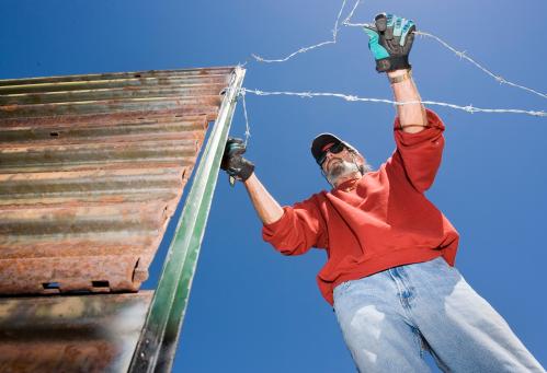 "Minuteman Project" volunteer Bill Povondra strings barbed wire from the existing border fence as part of a project to build a privately funded fence along the US/Mexico border, to keep out undocumented immigrants, in Boulevard, California April 29, 2006. There is a fence erected along part of the border in the area, but the "Minuteman Project" wanted to bridge the gaps with a privately financed fence of their own built between the government built sections. More than 100 volunteers participated in the daylong event. Boulevard is about 65 miles (104.6 km) east of downtown San Diego. REUTERS/Fred Greaves