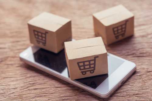 Online shopping - Paper cartons or parcel with a shopping cart logo and smartphone on wood table top