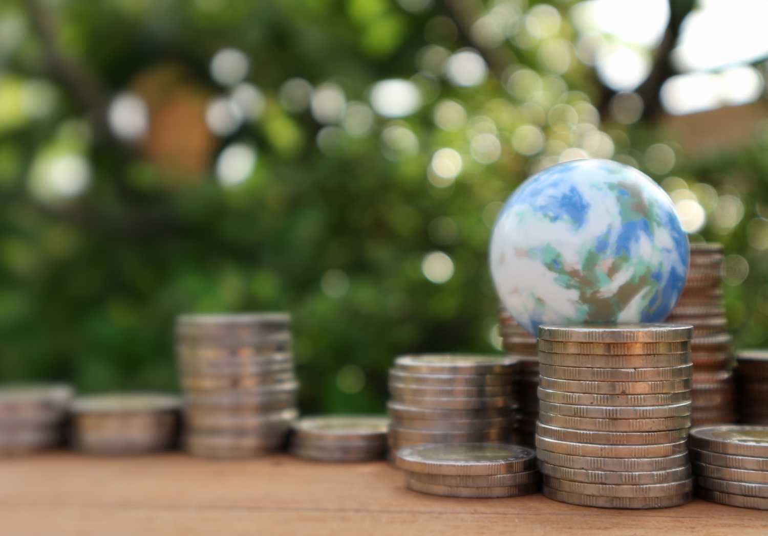 stacks of coins in front of a globe