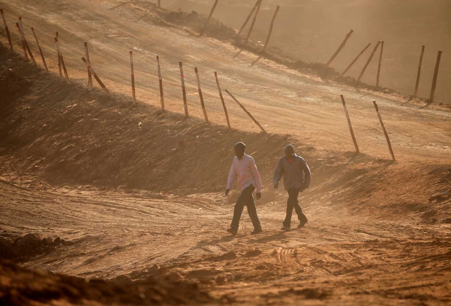 Men walk on a road under construction.