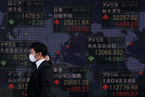 A man wearing a face mask as a preventive measure against the spread of Covid-19 walks past an electronic board showing currency exchange rates at a securities firm in Tokyo. Tokyo stocks ended higher Thursday on gains in other Asian markets and expectations for a U.S. economic recovery after the Congress passed a $1.9 trillion coronavirus relief package overnight. (Photo by James Matsumoto / SOPA Images/Sipa USA)No Use Germany.