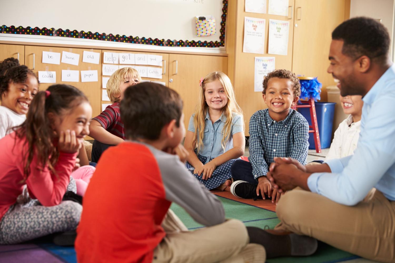 Children sit cross-legged learning together in a classroom.