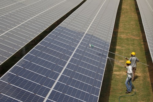 FILE PHOTO: Workers clean photovoltaic panels inside a solar power plant in Gujarat, India, July 2, 2015. India's $100 billion push into solar energy over the next decade will be driven by foreign players as uncompetitive local manufacturers fall by the wayside, no longer protected by government restrictions on the sector. REUTERS/Amit Dave/File Photo