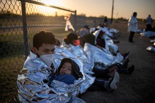 Dustin, an asylum-seeking migrant from Honduras, holds his six-year-old son Jerrardo, 6, as they awake at sunrise next to others who took refuge near a baseball field after crossing the Rio Grande river into the United States from Mexico on rafts, in La Joya, Texas, U.S., March 19, 2021. Emergency blankets were provided to the group of about 150 migrants from Central America by the U.S. Border Patrol agents. REUTERS/Adrees Latif     TPX IMAGES OF THE DAY