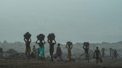 coal workers carrying coal on their heads in a hazy coal quarry