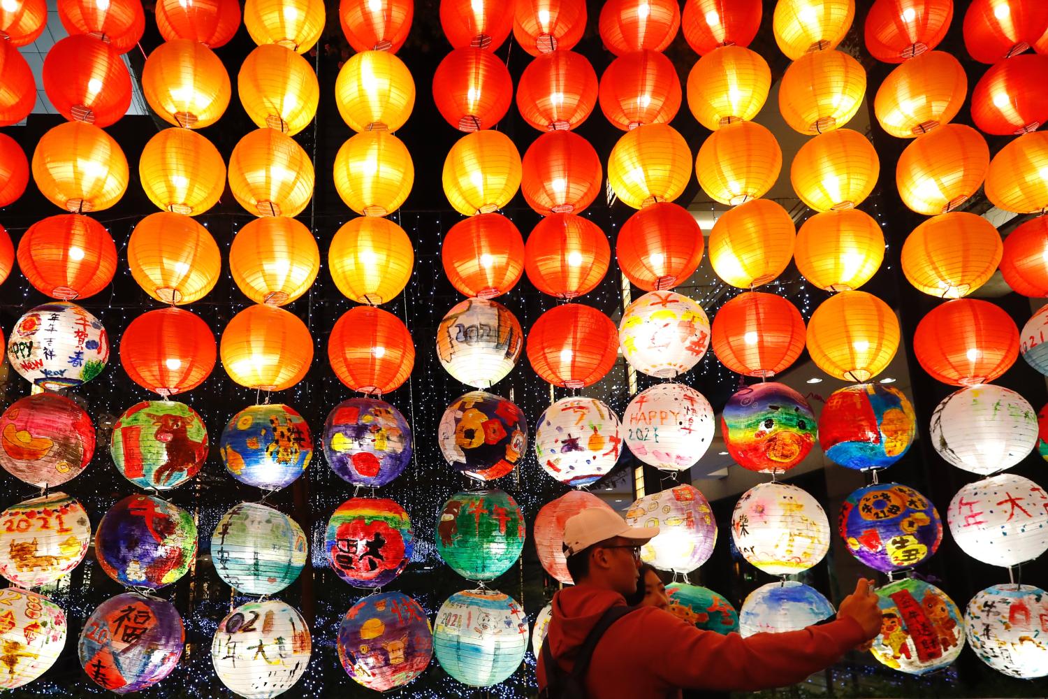 People taking selfies near a footbridge decorated with lanterns ahead of the Lunar New Year, amid the Covid-19 pandemic.The island country will see few people in the streets as events, activities and gatherings for festival celebration have been cancelled or postponed to avoid the transmission subsequent to a cluster of domestic outbreak. (Photo by Daniel Tsang / SOPA Images/Sipa USA)No Use Germany.