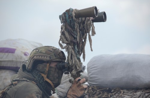 A service member of the Ukrainian armed forces uses binoculars while observing the area at fighting positions on the line of separation near the rebel-controlled city of Donetsk, Ukraine April 6, 2021. REUTERS/Serhiy Takhmazov