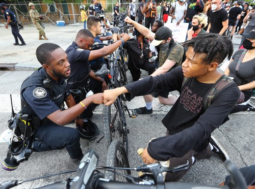 Atlanta Police officer J. Coleman, left, and protester Elijah Raffington give each other a fist bump while an Atlanta Police bicycle unit blocking Marietta Street at Centennial Olympic Park Drive kneels down with protesters outside the CNN Center at Olympic Park during a sixth day of protests over the death of George Floyd in Minneapolis police custody on Wednesday, June 3, 2020. Photo by Curtis Compton/Atlanta Journal-Constitution/TNS/ABACAPRESS.COM