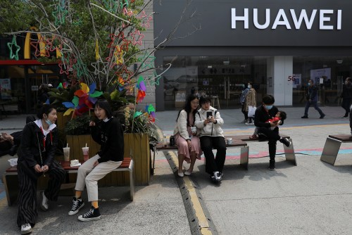 People rest in front of a Huawei store at a shopping complex in Beijing, China April 15, 2021. Picture taken April 15, 2021. REUTERS/Tingshu Wang