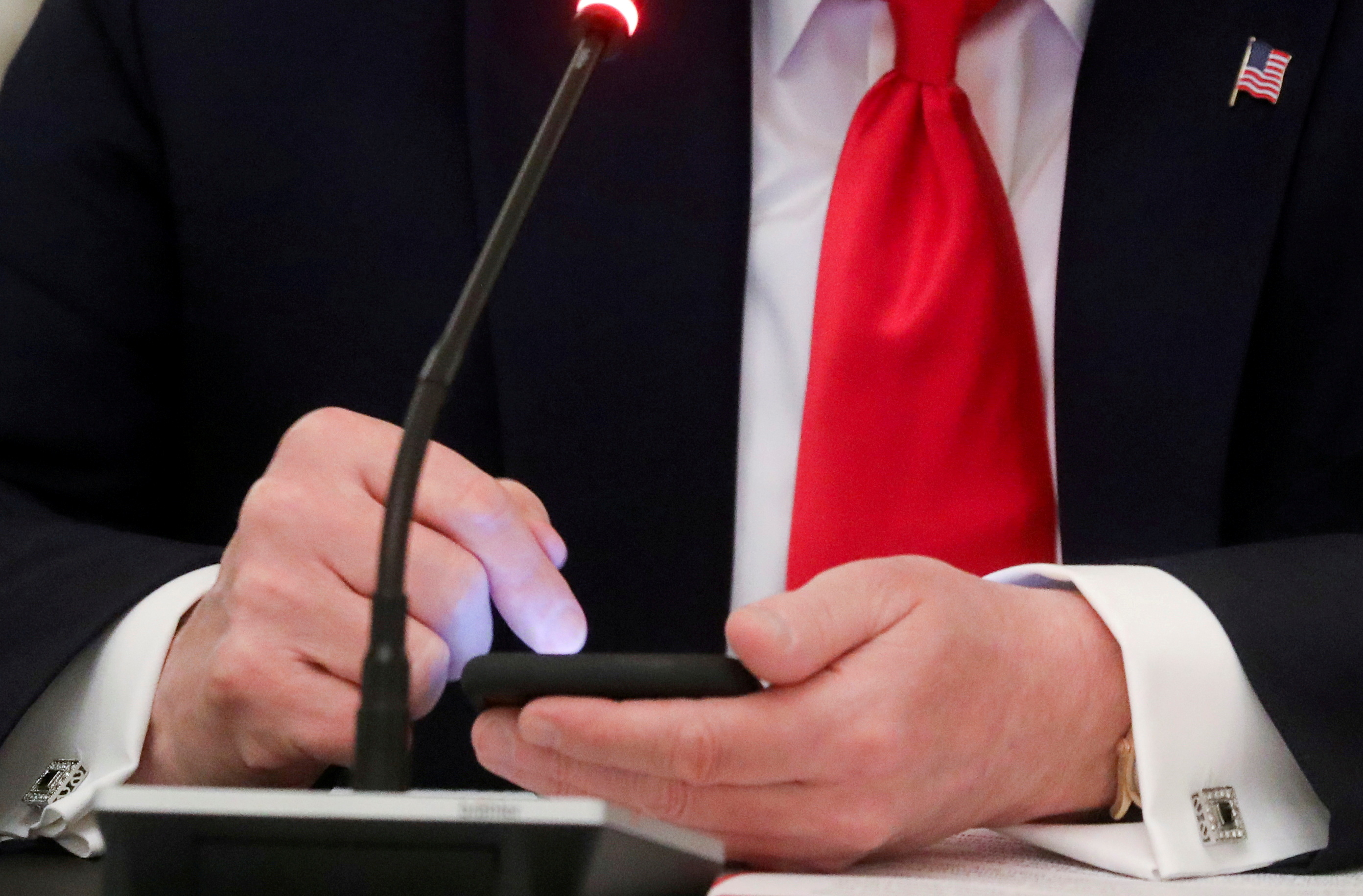 FILE PHOTO: U.S. President Donald Trump taps the screen on a mobile phone  in the State Dining Room at the White House in Washington, U.S., June 18, 2020. REUTERS/Leah Millis/File Photo