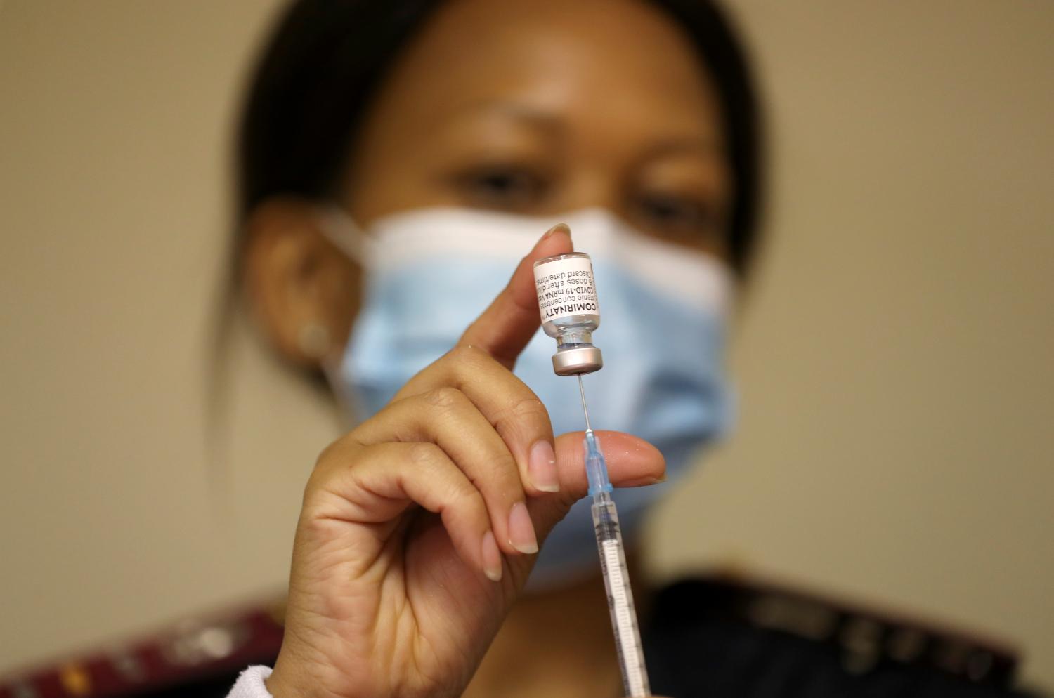 A health worker holds a vial of the Pfizer/BioNTech coronavirus disease (COVID-19) vaccine, at the Munsieville Care for the Aged Centre outside Johannesburg, South Africa May 17, 2021. REUTERS/Siphiwe Sibeko