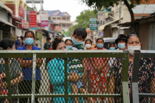 Oum Sreykhouch carries her child as she stands with her neighbours behind a lockdown barrier to ask for food donations after their village has been closed for more than two weeks inside a red zone with strict lockdown measures during the latest outbreak of the coronavirus disease (COVID-19) in Phnom Penh, Cambodia, April 30, 2021. REUTERS/Cindy Liu