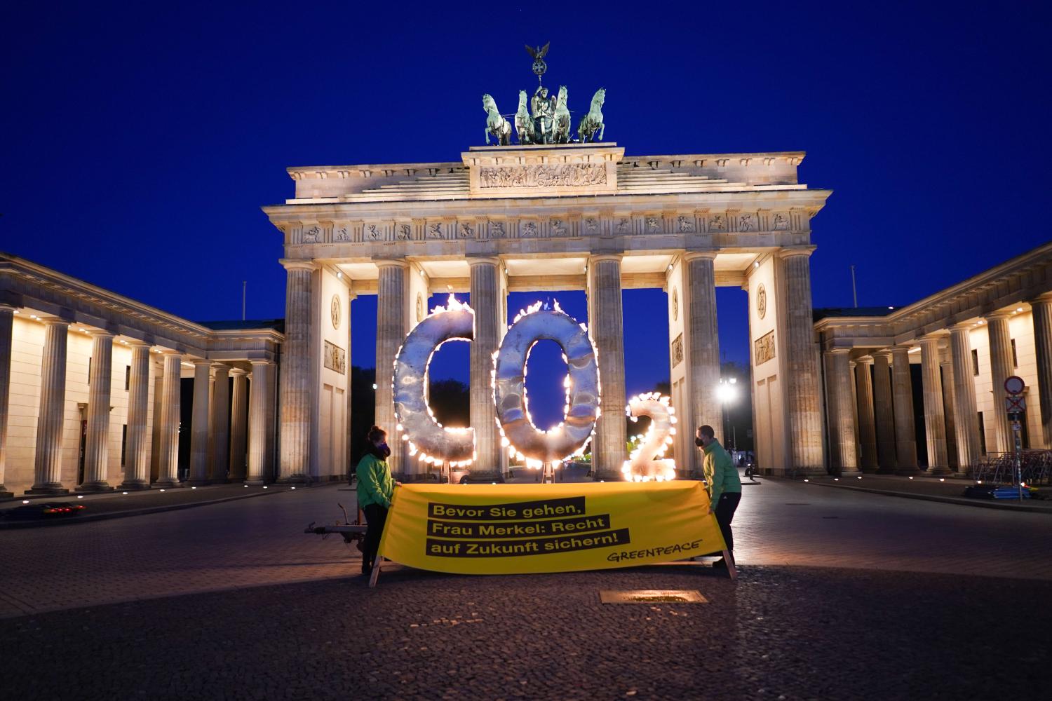 During a Greenpeace action, a CO-2 sign stands in front of the Brandenburg Gate with flames coming out of it. Two demonstrators hold a banner with the words "Before you go Mrs Merkel: Secure the future". With the action, activists of the environmental protection organization call on the German government to further reduce CO-2 emissions in Germany and to ensure compliance with the goals of the world climate summit in Paris.
