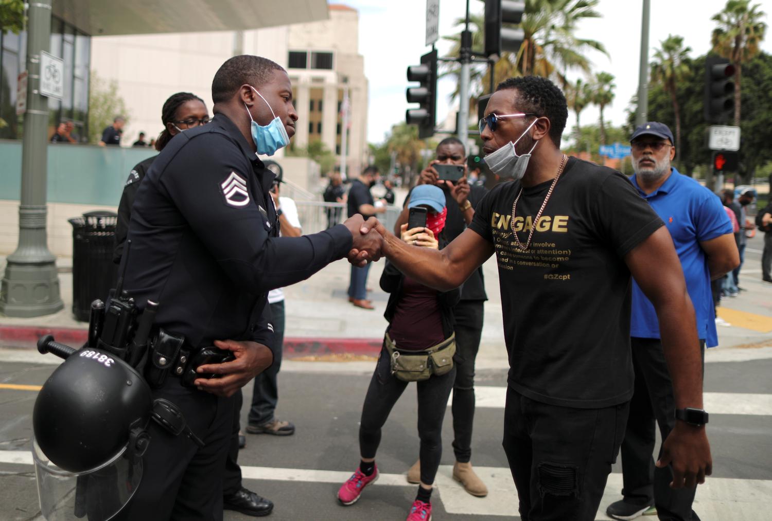 A police officer shakes hands with a demonstrator during a protest against the death in Minneapolis police custody of George Floyd, outside LAPD headquarters in Los Angeles, California, U.S. June 2, 2020. REUTERS/Lucy Nicholson