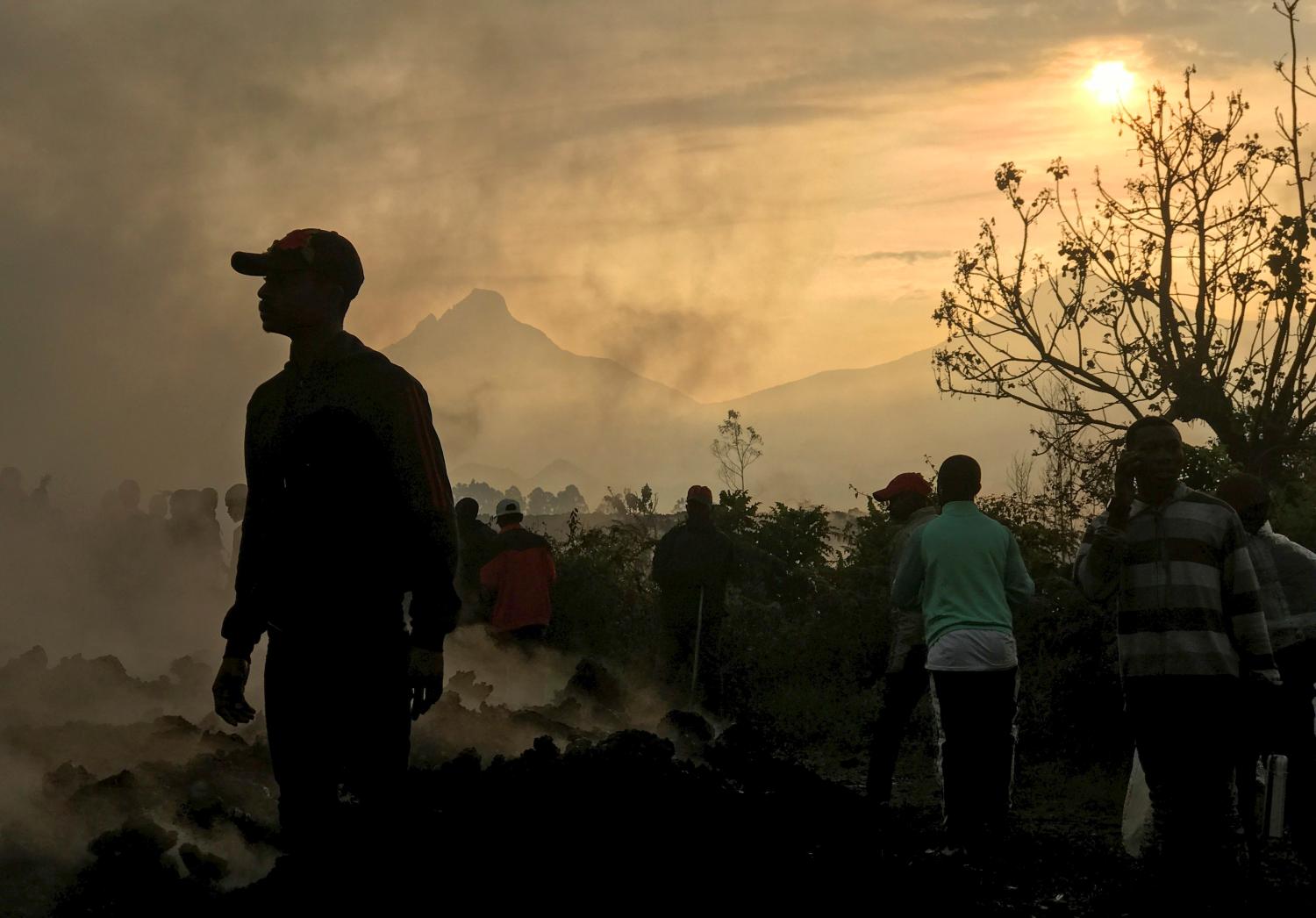 Residents walk near destroyed homes with the smouldering lava deposited by the eruption of Mount Nyiragongo volcano near Goma, in the Democratic Republic of Congo May 23, 2021. REUTERS/Djaffar Al Katanty       NO RESALES. NO ARCHIVES.     TPX IMAGES OF THE DAY