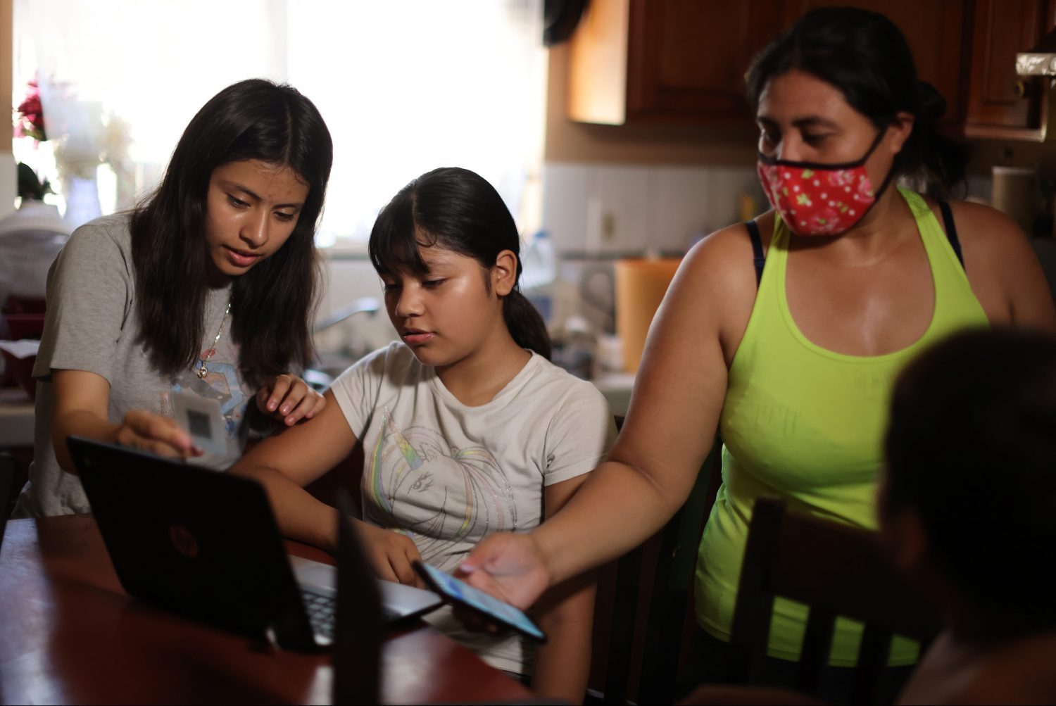 Los Angeles Unified School District (LAUSD) students Keiley Flores, 13, Andrea Ramos, 10, and Alexander Ramos, 8, work on school-issued computers with unreliable internet connectivity, as their mother Anely Solis, 32, tries to connect them to her mobile hotspot, during the global outbreak of the coronavirus disease (COVID-19), at their home in Los Angeles, California, U.S., August 18, 2020.  REUTERS/Lucy Nicholson