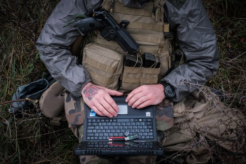 A French soldier is seen operating a laptop computer while seated.