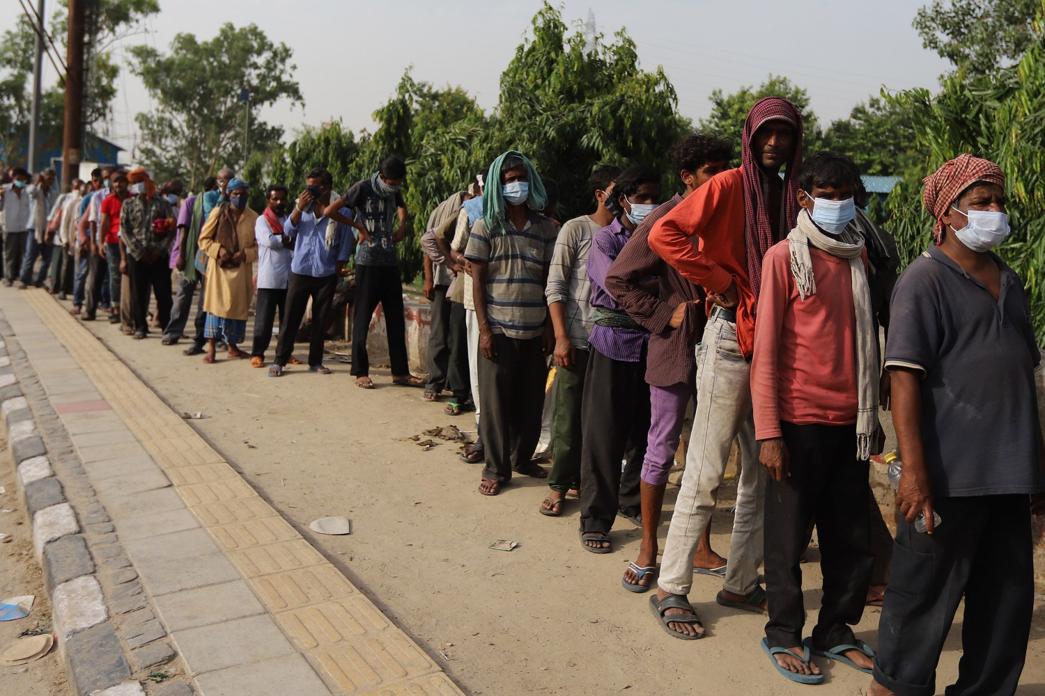 Daily wage laborers and homeless people wait in a queue to receive free food during a lockdown imposed to curb the spread of the coronavirus disease in New Delhi. (Photo by Amarjeet Kumar Singh / SOPA Images/Sipa USA)No Use Germany.