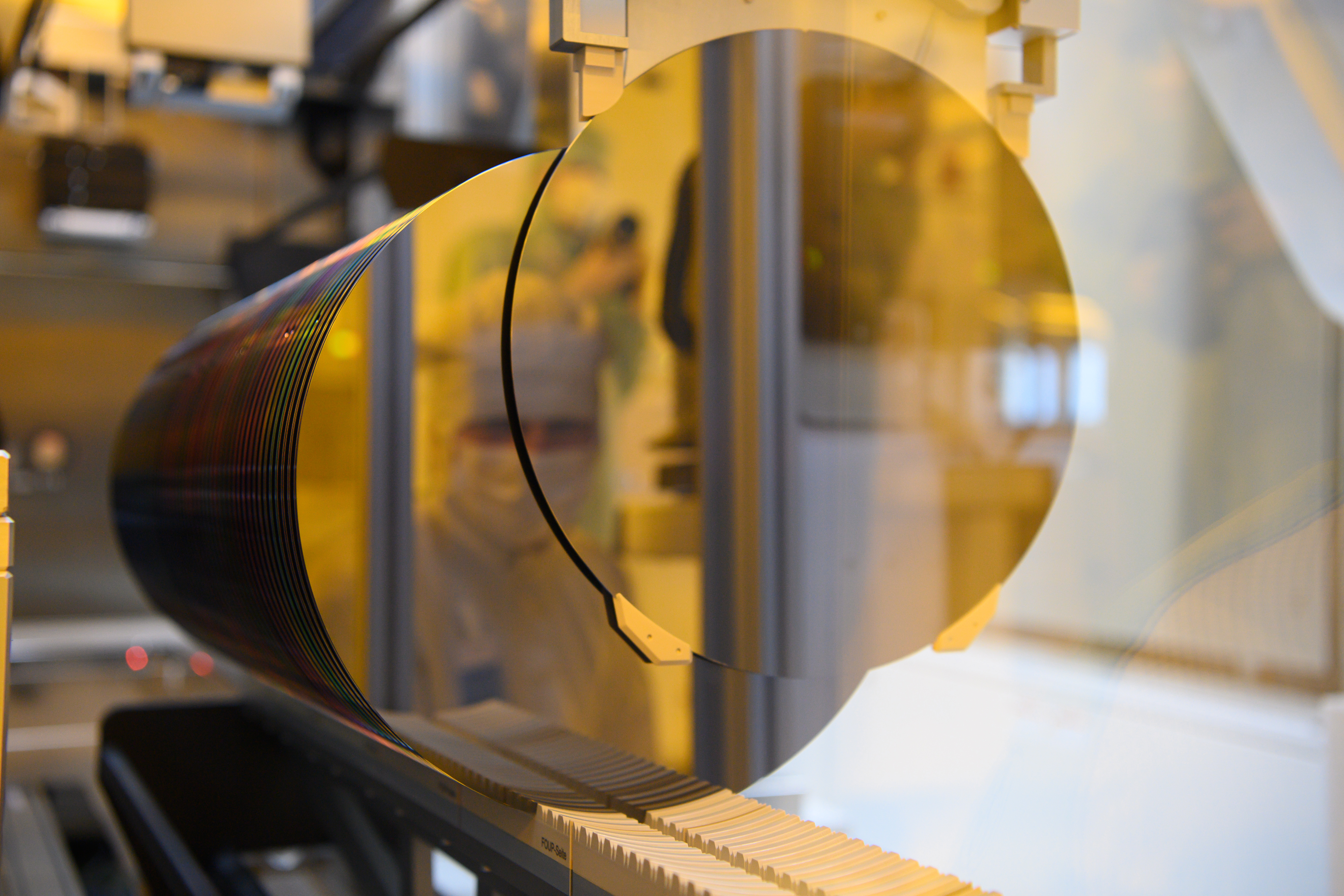 An associate is reflected in a 300-millimeter wafer in the clean room during a press tour of Bosch's new semiconductor factory. The chip factory will officially go into operation on June 7, 2021.