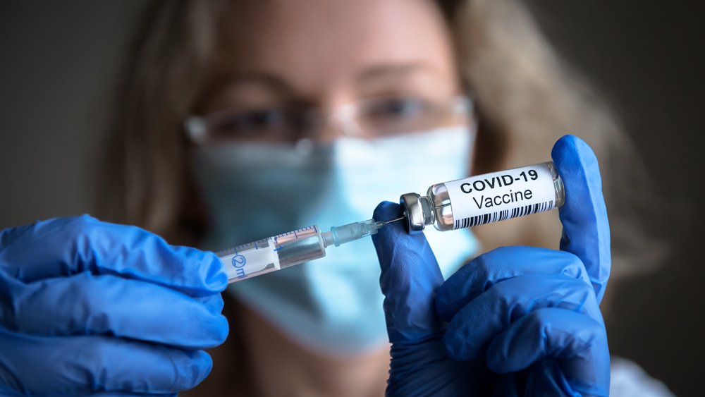 COVID-19 vaccine in researcher hands, doctor holds syringe and bottle with vaccine for coronavirus cure.