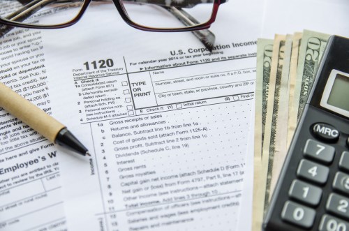Corporate income tax form with pile of money and calculator.