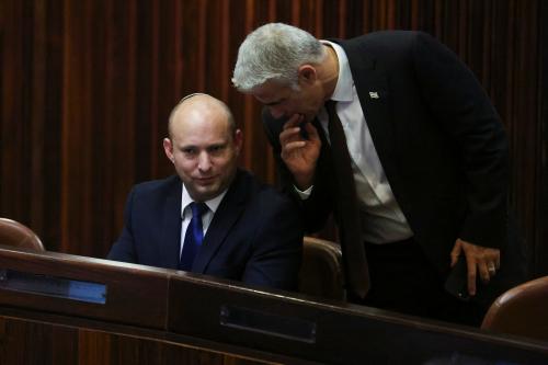 Yamina party leader Naftali Bennett smiles as he speaks to Yesh Atid party leader Yair Lapid, during a special session of the Knesset whereby Israeli lawmakers elect a new president, at the plenum in the Knesset, Israel's parliament, in Jerusalem June 2, 2021. REUTERS/Ronen Zvulun